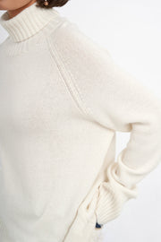 Sand cashmere turtleneck sweater with raglan sleeves and ribbed cuffs.