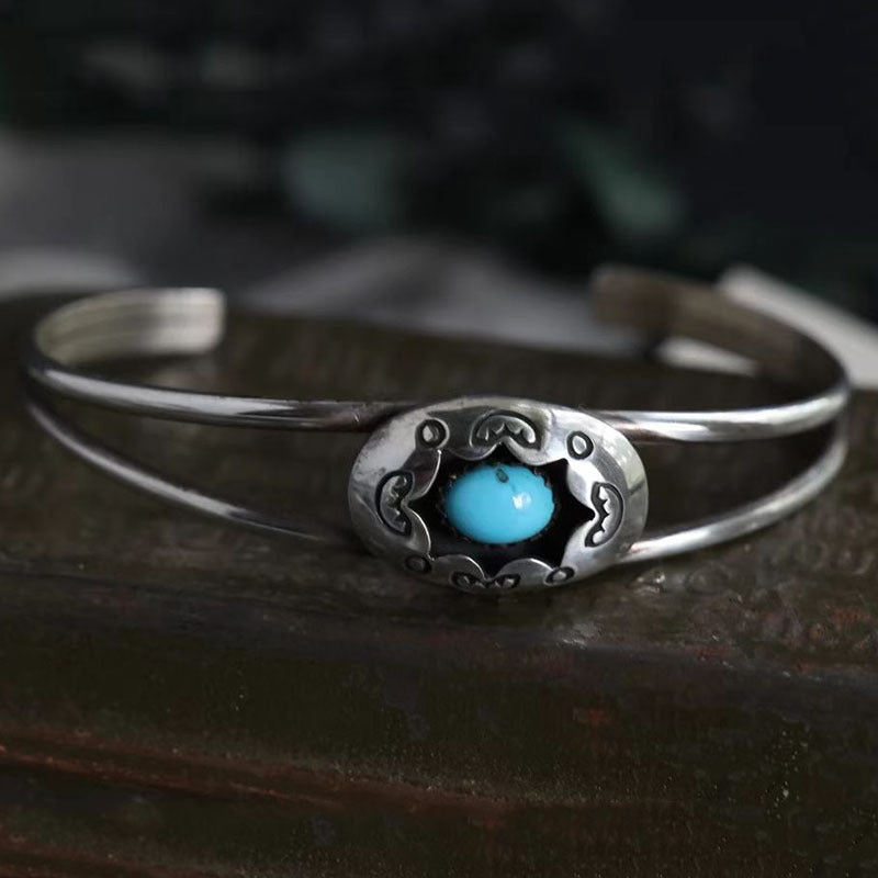 Turquoise cuff bracelet with oval center stone and decorative metalwork