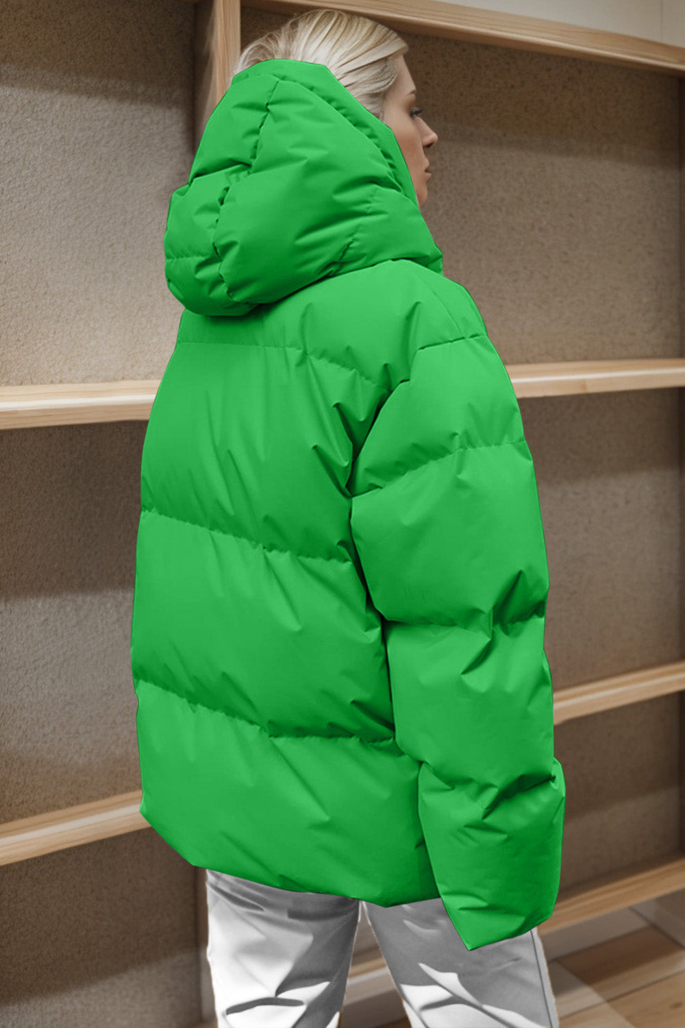 Green oversized puffer jacket with hood and horizontal quilting detail.