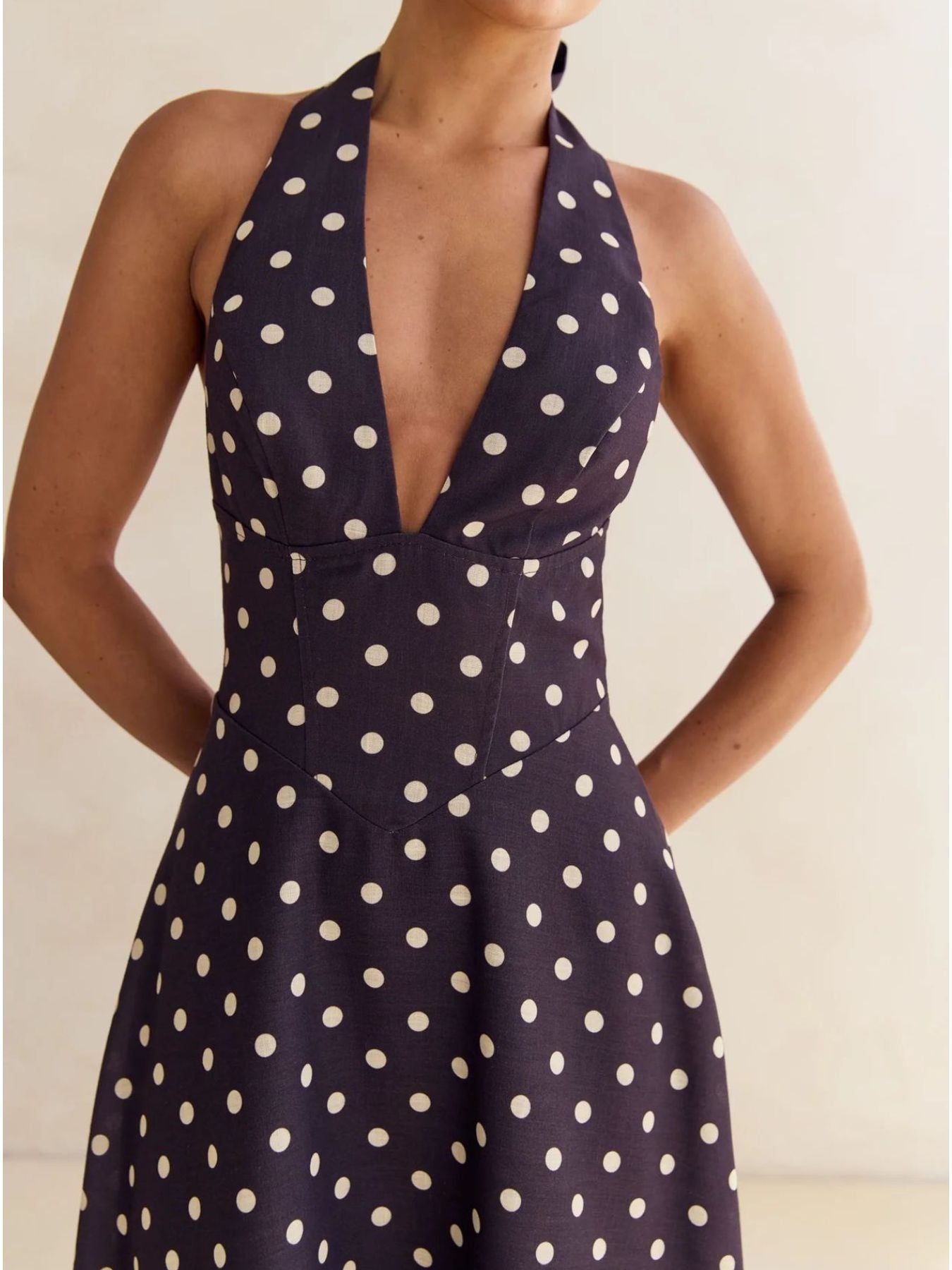Navy polka dot halter neck maxi dress with a deep V-neck and A-line skirt.