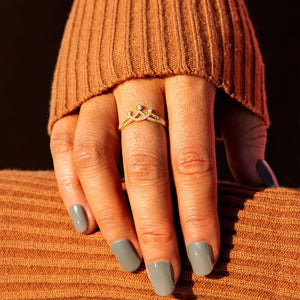Gold pave crown ring with small diamonds on a hand wearing a brown sweater.