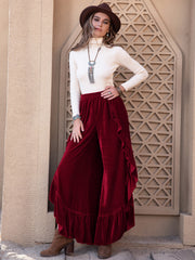 Burgundy velvet palazzo pants with ruffle slit detail and ruffled hem.