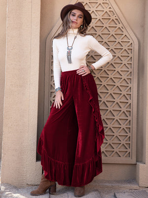 Burgundy velvet palazzo pants with ruffle slit detail and ruffled hem.