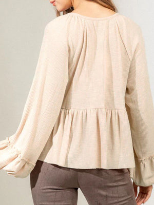 Textured ribbed peplum blouse in tan with ruffled cuffs and balloon sleeves.