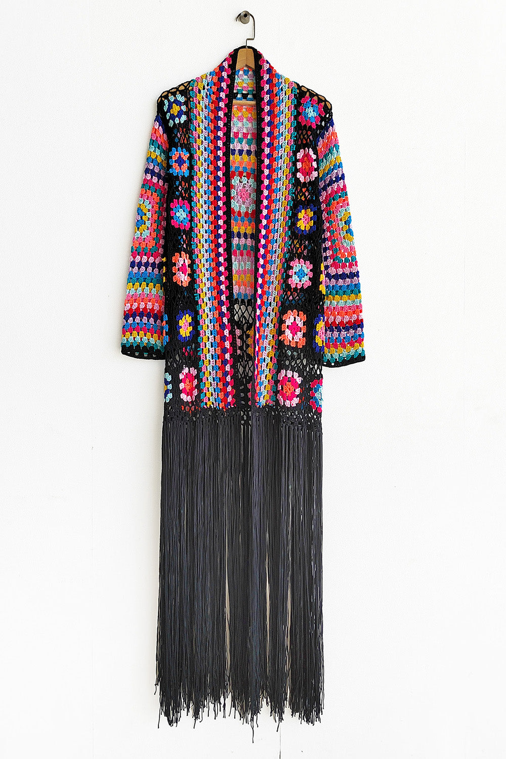 Granny square crochet duster with black fringe, open front, long sleeves, and colorful boho pattern.