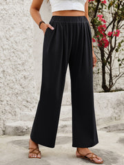 Black wide leg trousers with elastic waistband and pockets, styled with sandals.