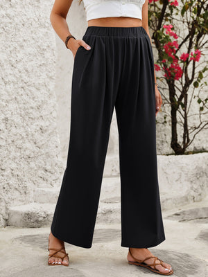 Black wide leg trousers with elastic waistband and pockets, styled with sandals.