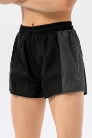 Black and dark grey colorblock performance running shorts with drawstring waist.
