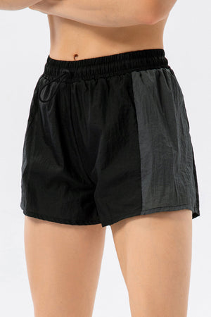 Black and dark grey colorblock performance running shorts with drawstring waist.