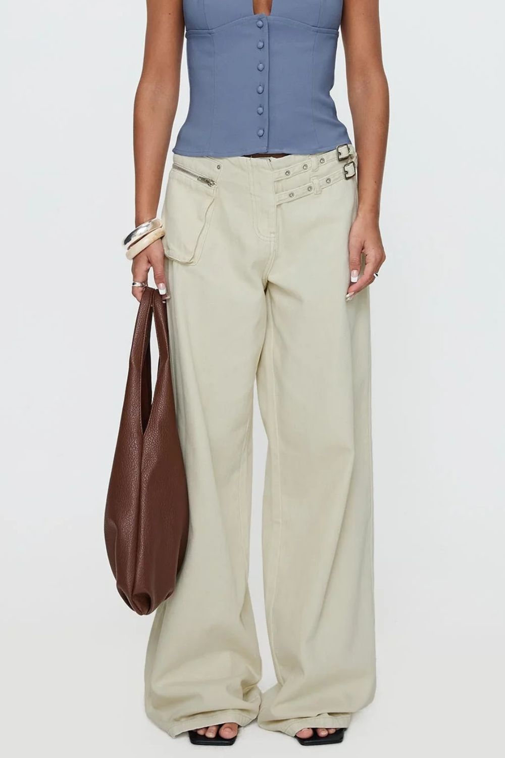 Cream cotton flared jeans with utility pockets and buckle details.