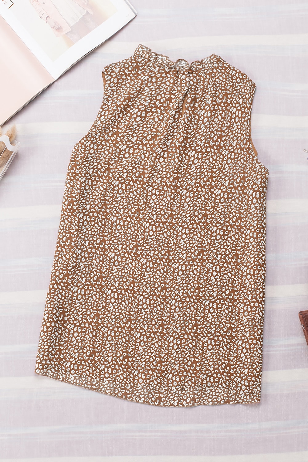 Brown printed sleeveless blouse with ruffled neckline.