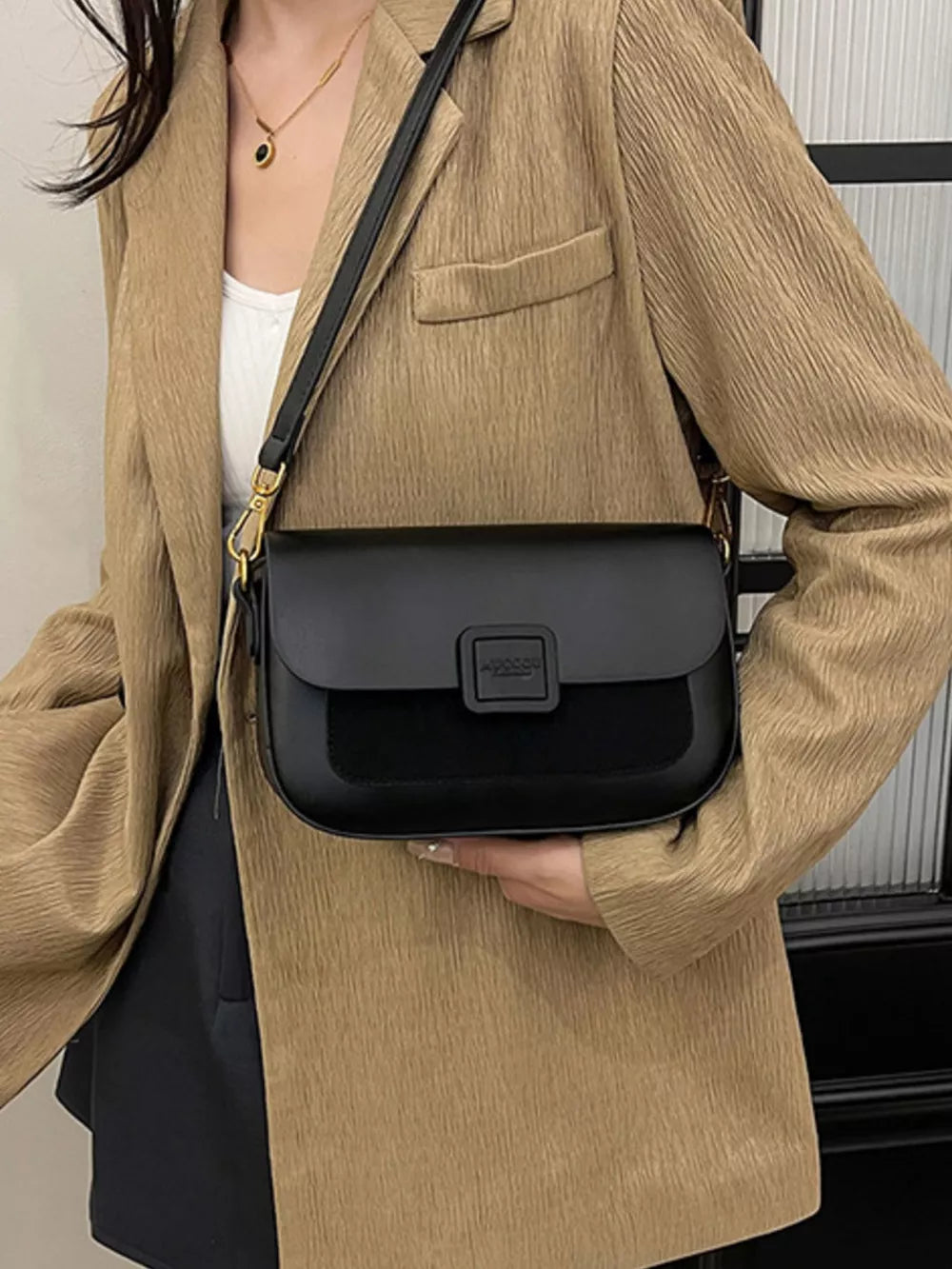 Chic two-tone crossbody bag in black with suede panel and buckle closure.