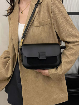 Chic two-tone crossbody bag in black with suede panel and buckle closure.