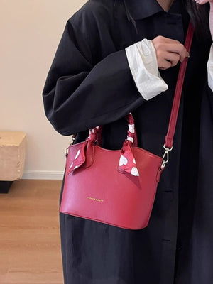 Red pu leather bucket bag with heart print scarf and adjustable strap.