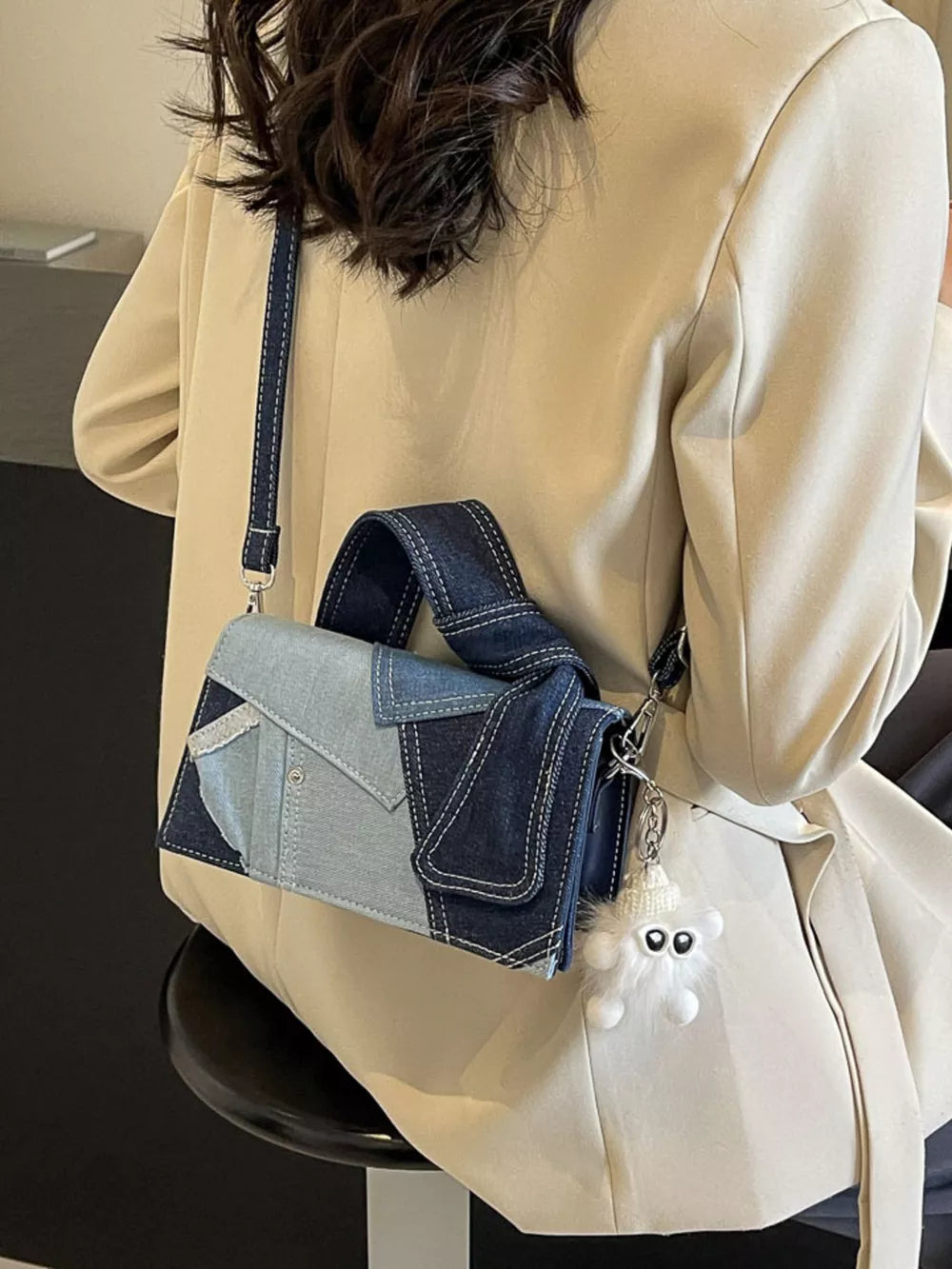 Artisanal denim crossbody bag with patchwork design and fluffy charm
