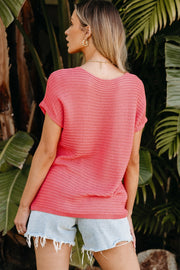 Open-knit dolman sleeve top in watermelon pink acrylic with a boat neckline.