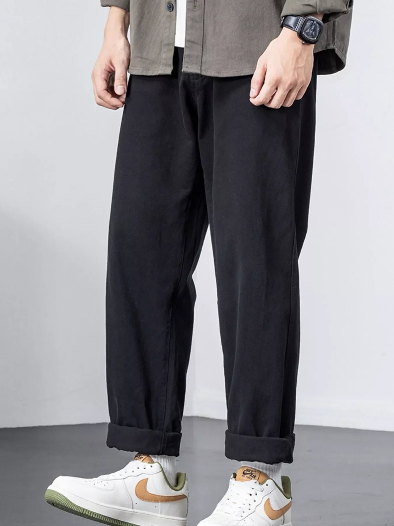 Black cotton wide-leg trousers with cuffed hems, styled casually.