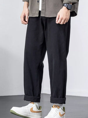 Black cotton wide-leg trousers with cuffed hems, styled casually.
