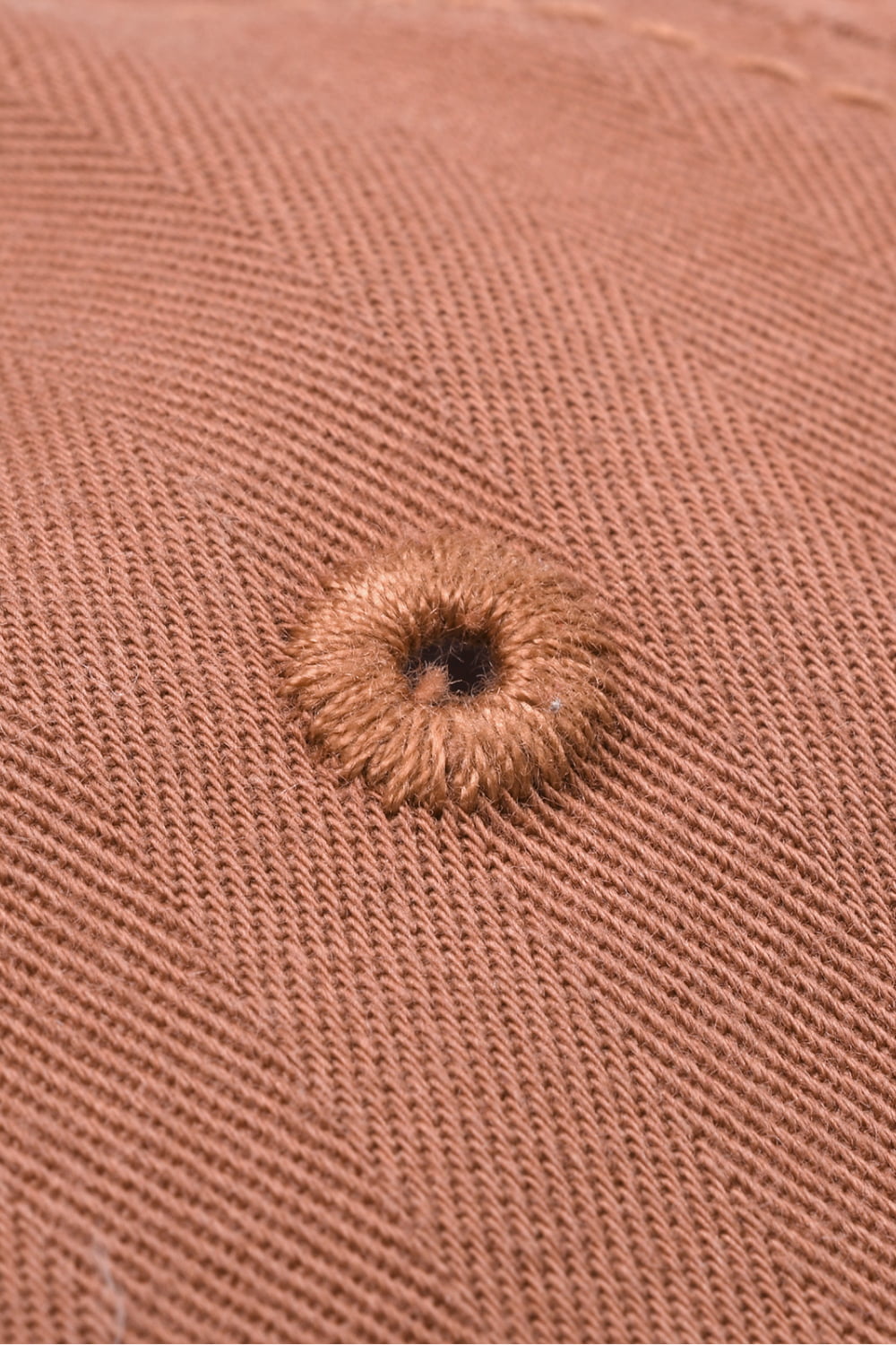 Coral baseball cap with herringbone texture and embroidered eyelet detail