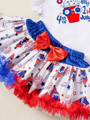 Baby girl's festive outfit with gnome and firework print skirt, red bow, and ruffled hem.