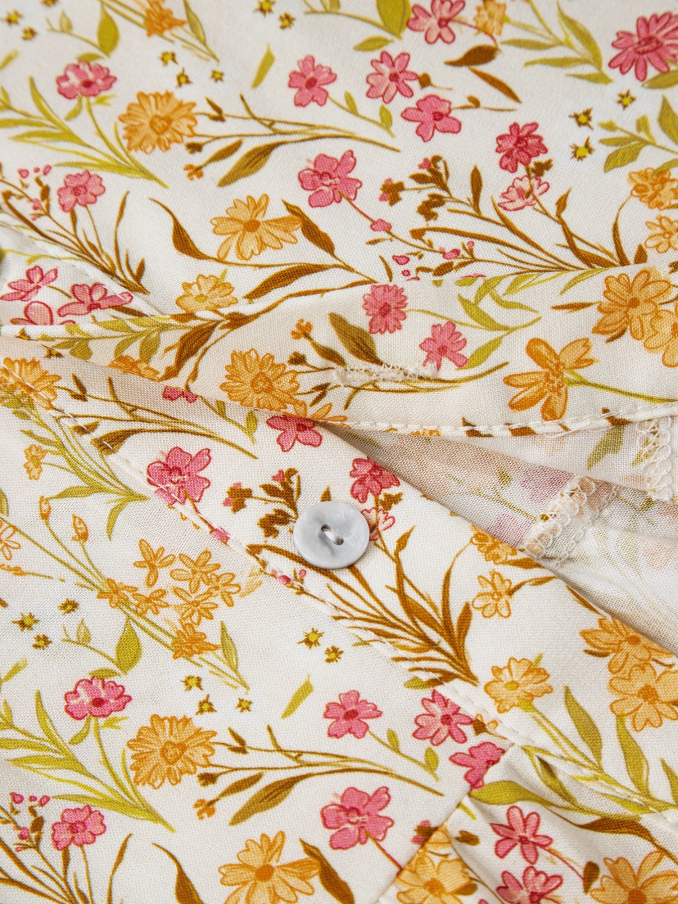Floral print button-down shirt dress with pink and orange flowers on white fabric.