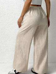 Relaxed beige cotton wide-leg pants with adjustable drawstring waist and textured fabric.