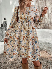 Charming floral tiered dress with long sleeves in beige, featuring a-line cut and ruffled cuffs.