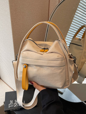 Khaki crossbody bag with yellow pull tab detail and adjustable strap.