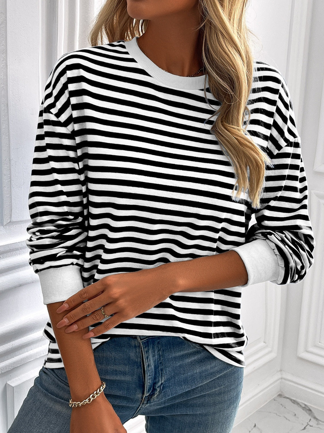 Black and white horizontal stripe crewneck sweatshirt with white cuffs.