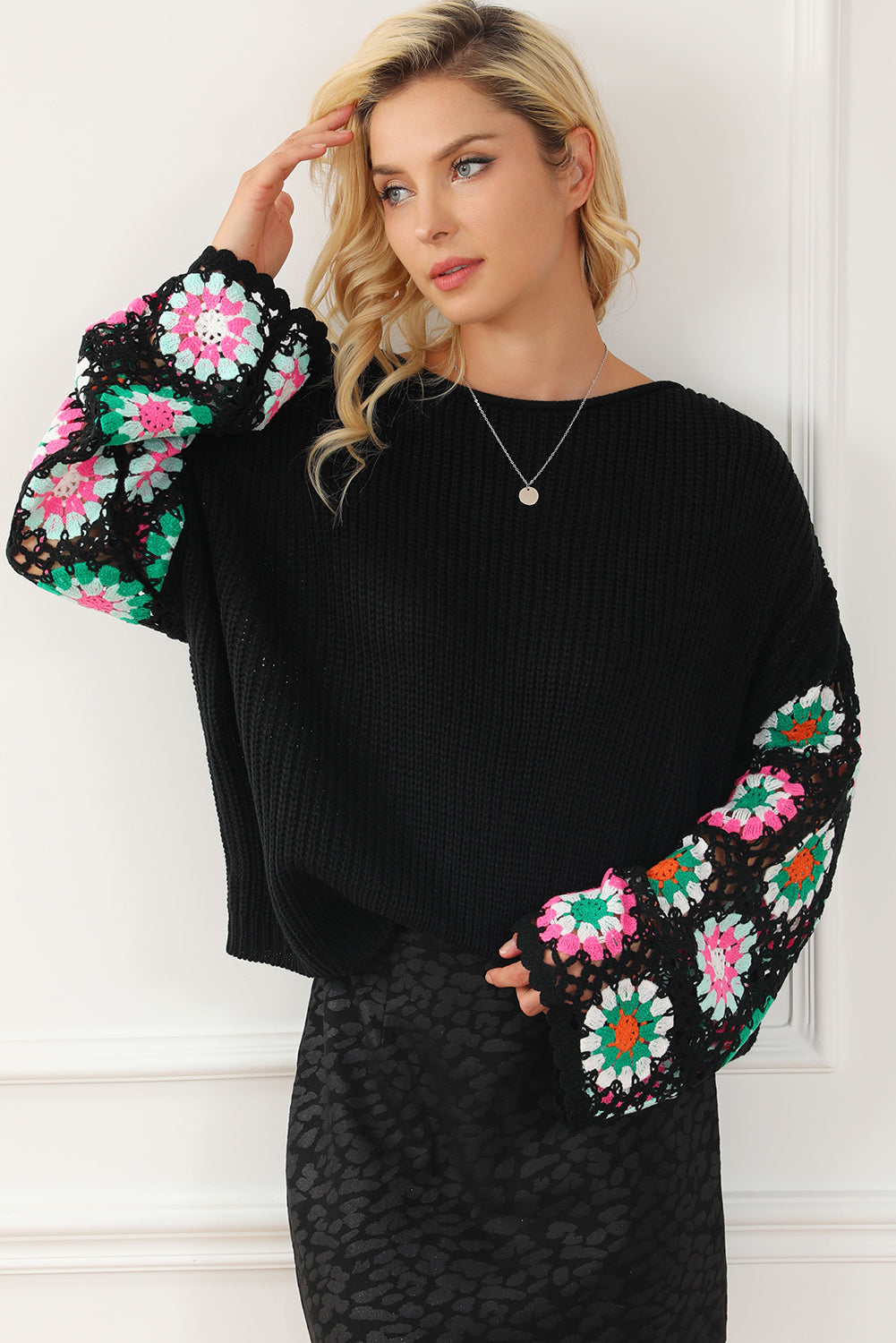 Black knit pullover sweater with crochet granny square sleeves in pink, green, and white.