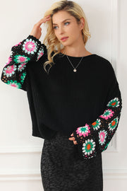Black knit pullover sweater with crochet granny square sleeves in pink, green, and white.