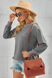 Gray sweatshirt with asymmetric hemline and raw edge detail, crew neck, long sleeves.