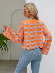 Orange-red crochet crop sweater with blue wave pattern and scalloped hem.