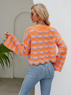 Orange-red crochet crop sweater with blue wave pattern and scalloped hem.