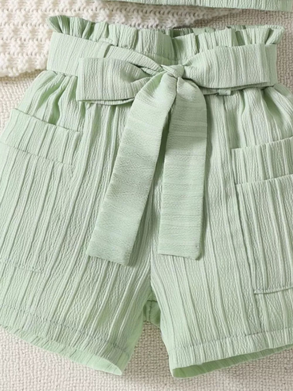 Light Green ribbed toddler shorts with ruffled waist and bow tie detail.