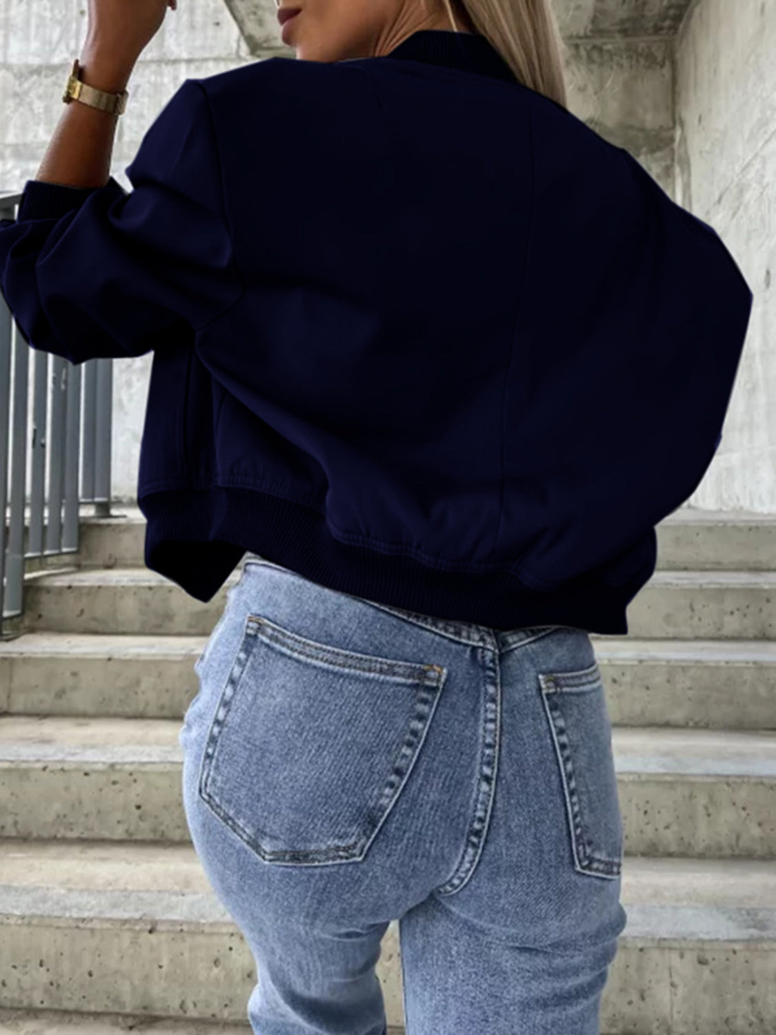 Navy faux leather bomber jacket with elastic cuffs and hem, styled with jeans.