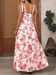 White maxi dress with red floral print, tie straps, smocked bodice, and tiered skirt.