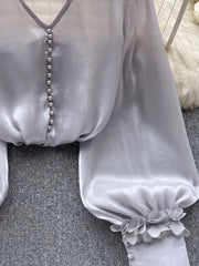 Gray sheer button-down shirt with pearl buttons and floral appliqué cuffs.