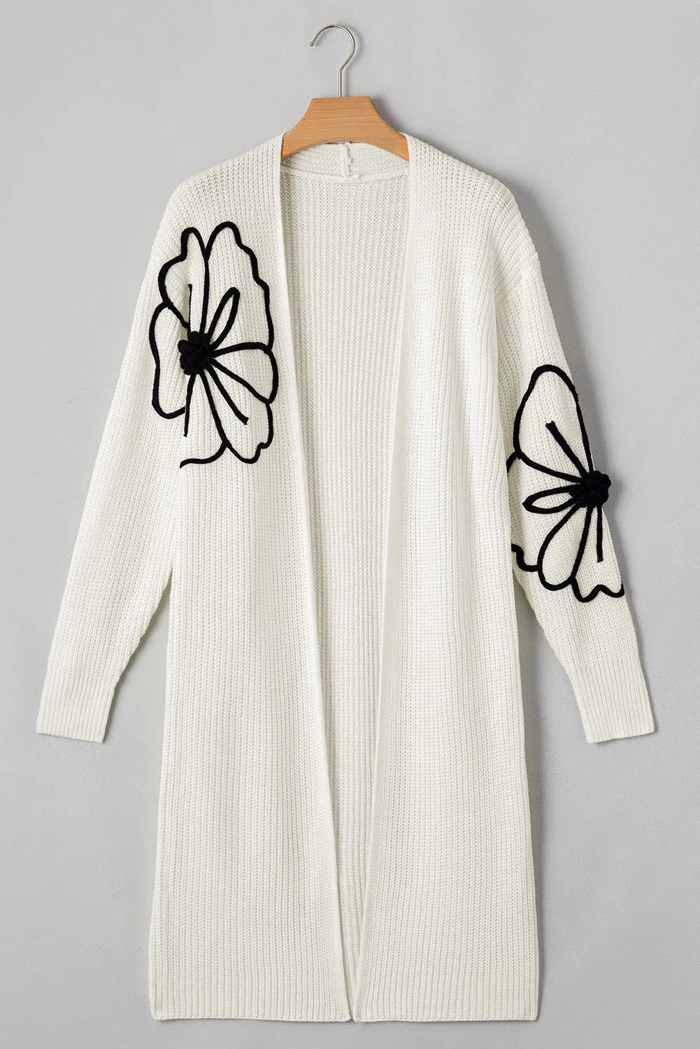 Ivory open-front maxi cardigan with black floral appliqué on sleeves.