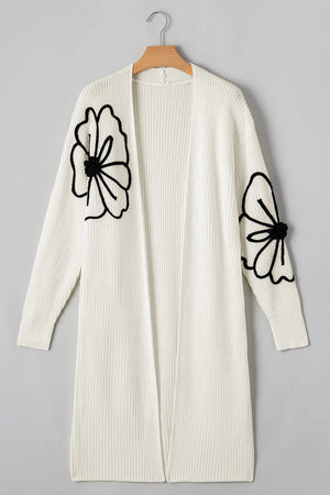 Ivory open-front maxi cardigan with black floral appliqué on sleeves.