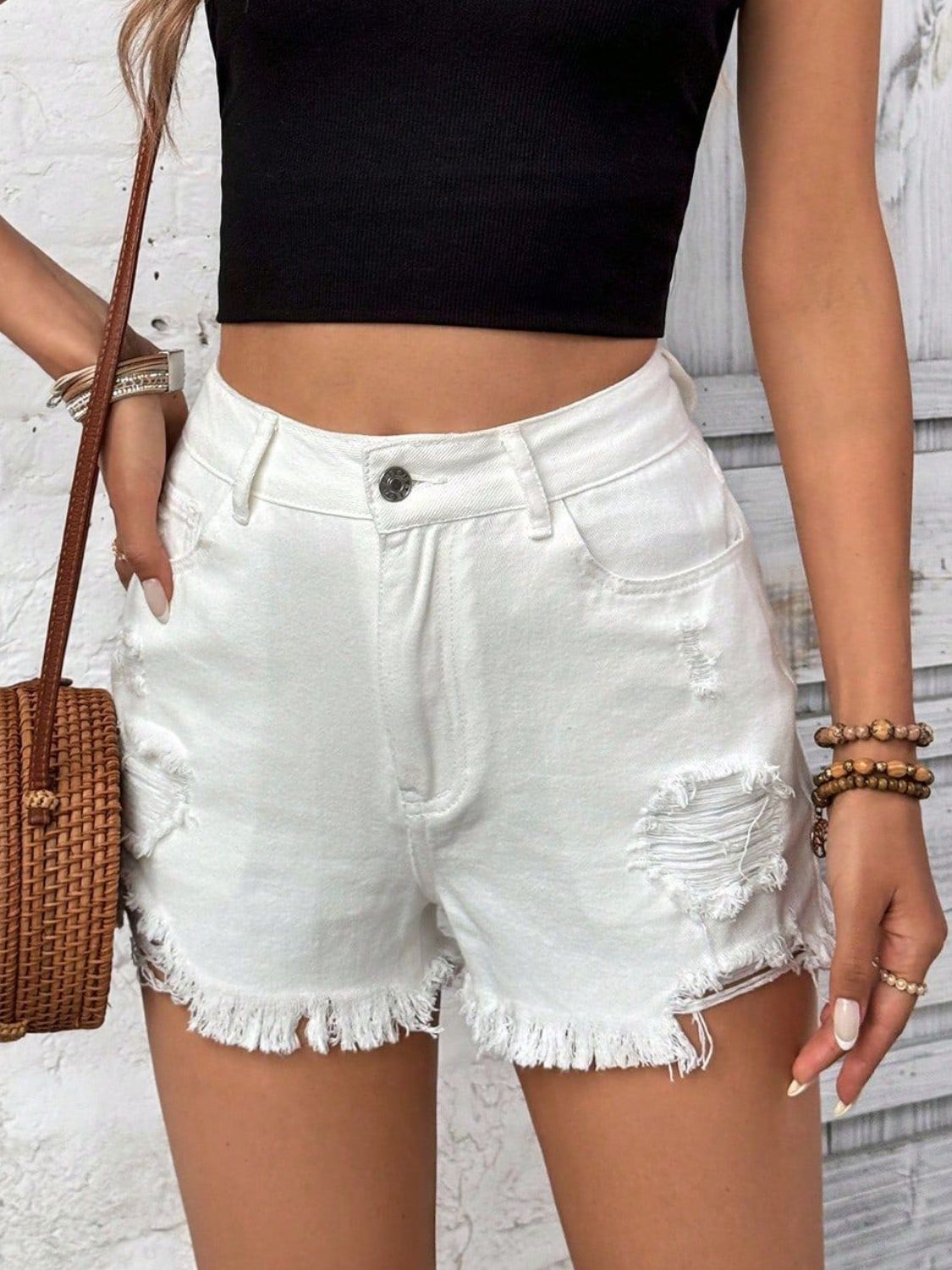 White distressed denim shorts with frayed hem and ripped details.