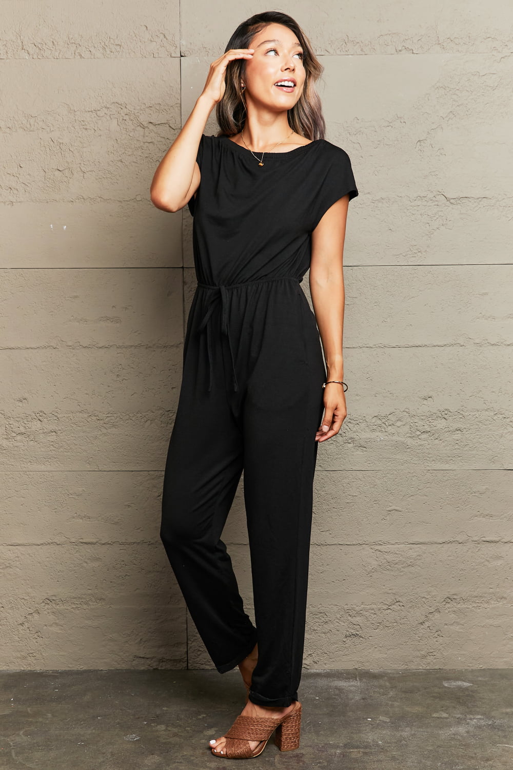Black cap sleeve jumpsuit with drawstring waist and boat neck.