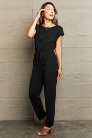 Black cap sleeve jumpsuit with drawstring waist and boat neck.