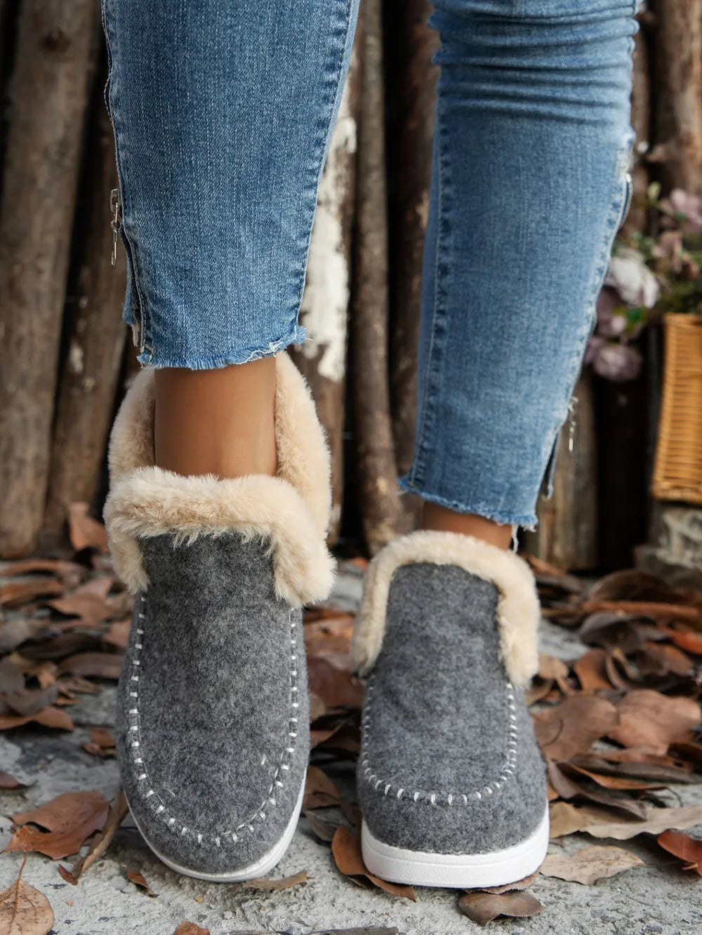 Gray felted slippers with faux shearling lining and white stitch detail.