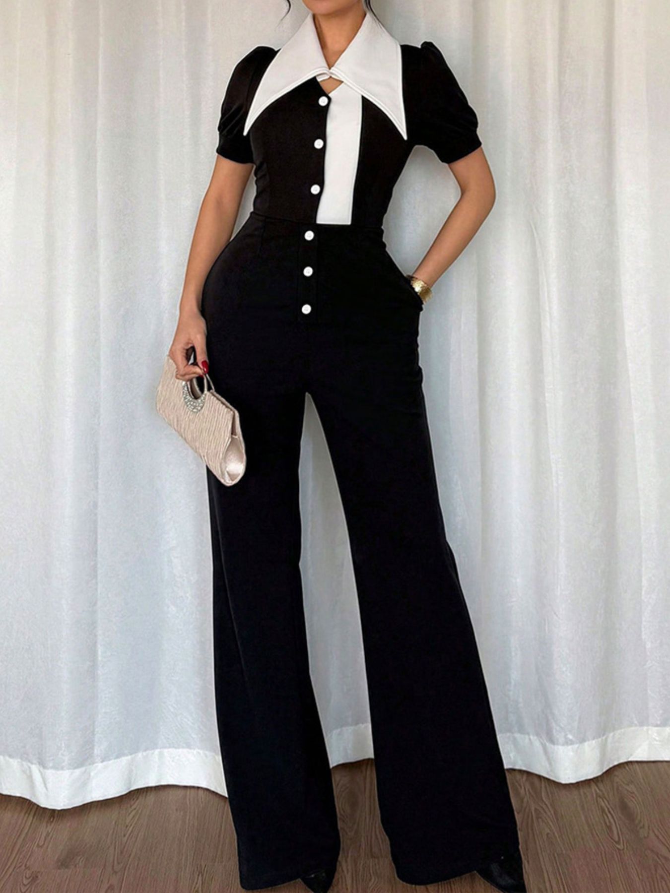 Button-down wide leg jumpsuit with a white collar and black body, featuring short sleeves and a button-up front.