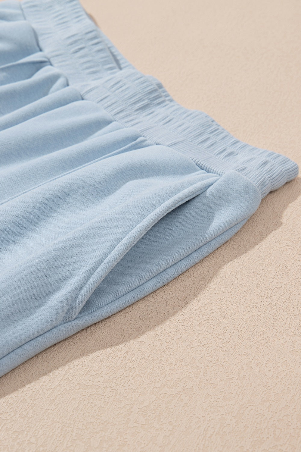 Light blue joggers with textured waistband and side pocket detail.