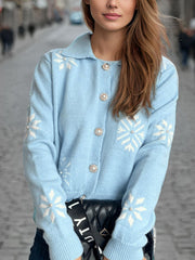 Pastel blue knit cardigan with snowflake pattern and pearl buttons, collared neckline.