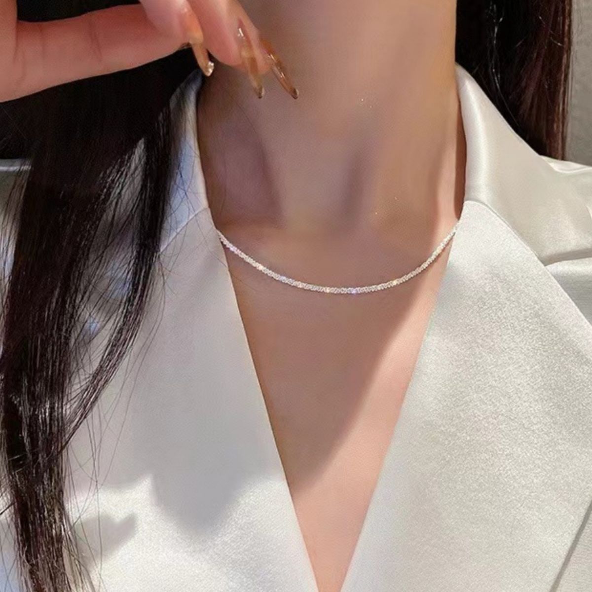 Sterling choker necklace with a delicate sparkle, worn close to the collarbone.