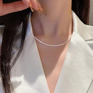 Sterling choker necklace with a delicate sparkle, worn close to the collarbone.