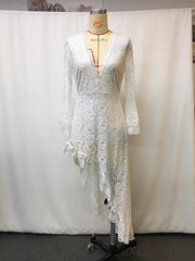 White lace asymmetrical V-neck dress with bell sleeves and ruffled hem.